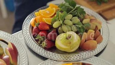 新鲜可口的梨、橘子、苹果、草莓和葡萄放在一个大银盘上，上面放着薄荷